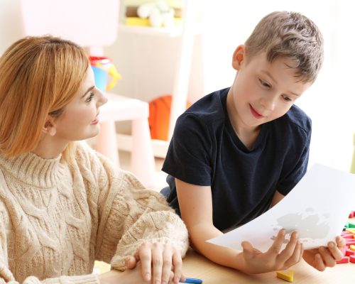 Female psychologist working with boy suffering from autistic disorder