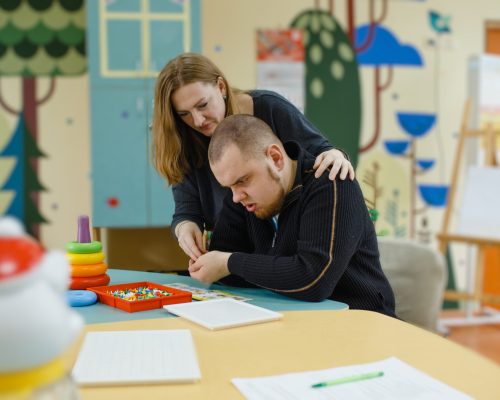 A female psychologist works with an adult boy with autism in the office. The concept of autism