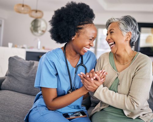 Smile, funny and assisted living caregiver with an old woman in her home during retirement together. Healthcare, support and a happy nurse or volunteer laughing with a senior patient on the sofa.